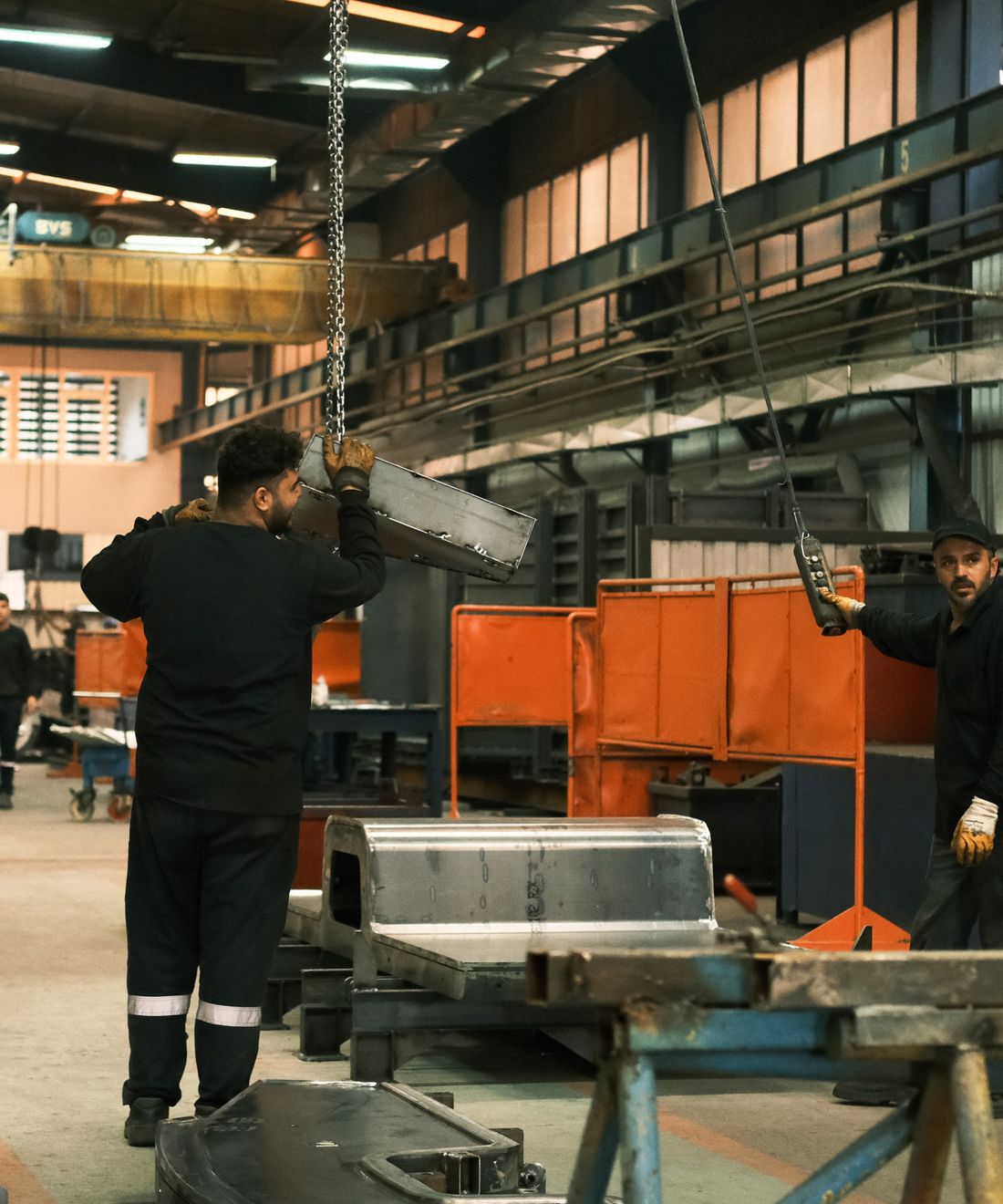 Productiemedewerkers werken aan een metalen onderdeel in de fabriek.